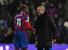 Pep Guardiola (R) shakes hands with Crystal Palace's Ivorian striker Wilfried Zaha (Photo by BEN STANSALL/AFP via Getty Images)