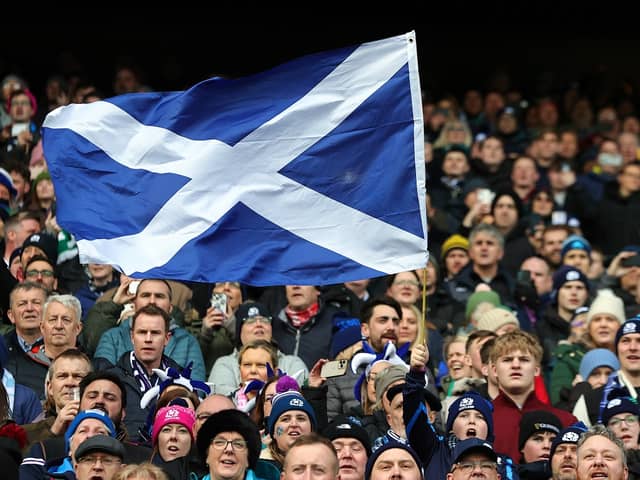 A Scotland fan waves a national flag as they enjoy the pre-match atmosphere prior to a Six Nations Rugby match at Murrayfield Stadium