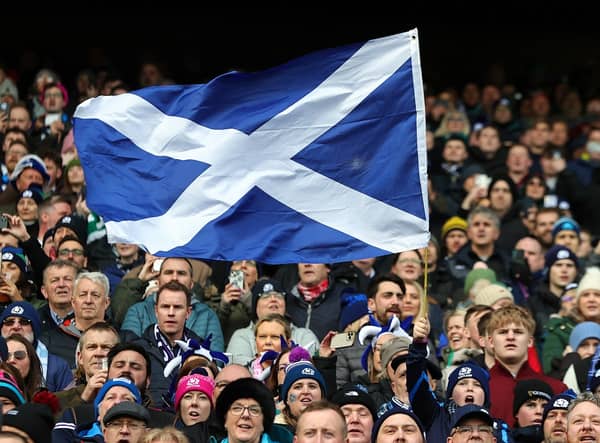 A Scotland fan waves a national flag as they enjoy the pre-match atmosphere prior to a Six Nations Rugby match at Murrayfield Stadium