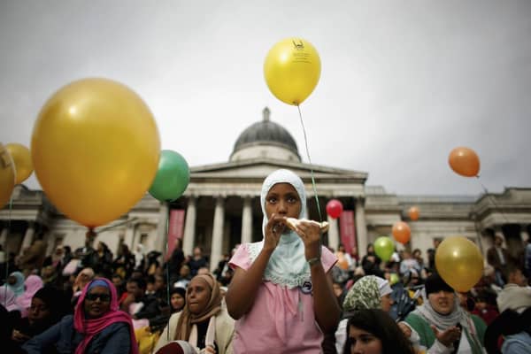 A young Muslim girl eats a sandwich as she looks on during Eid al-Fitr festivities on October 28, 2006 in London, England. (Photo by Daniel Berehulak/Getty Images)