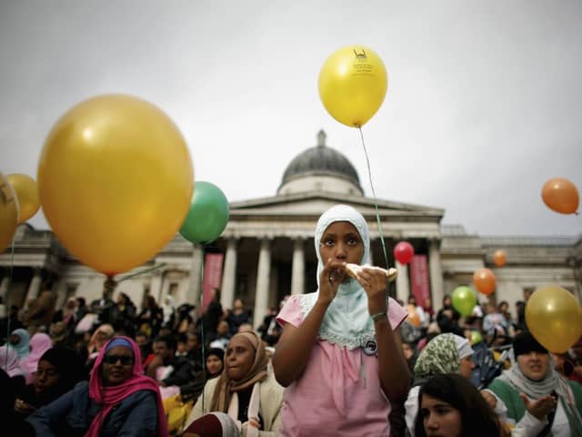 A young Muslim girl eats a sandwich as she looks on during Eid al-Fitr festivities on October 28, 2006 in London, England. (Photo by Daniel Berehulak/Getty Images)