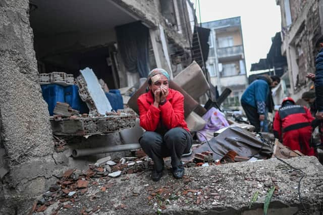 An earthquake survivor reacts as rescuers look for victims and other survivors in Hatay