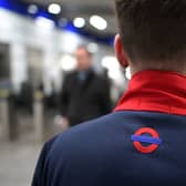 A member of staff looks on as people pass through a ticket barrier at Tottenham Court Road underground station 
