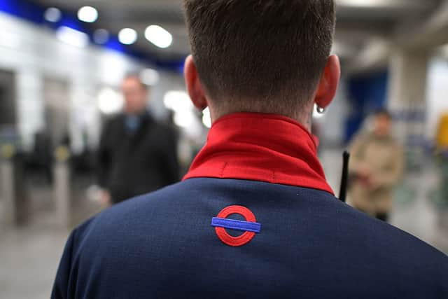 A member of staff looks on as people pass through a ticket barrier at Tottenham Court Road underground station 