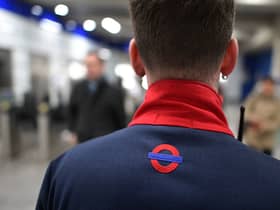 A member of staff looks on as people pass through a ticket barrier at Tottenham Court Road underground station 