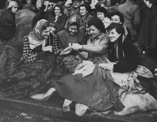 A group of spectators - Margaret Avory, Betty Cowell, Molly Mountford, and her sister Barbara Mountford - pass the time with a game of cards as they gather the day before the Coronation of Elizabeth II, on the procession route on The Mall on June 1, 1953. (Photo by Meager/Fox Photos/Hulton Archive/Getty Images)