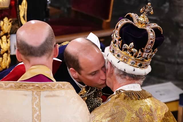 Prince William, Prince of Wales kisses his father, King Charles III, wearing St Edward's Crown, during the King's Coronation Ceremony inside Westminster Abbey on May 6, 2023 in London, England. The Coronation of Charles III and his wife, Camilla, as King and Queen of the United Kingdom of Great Britain and Northern Ireland, and the other Commonwealth realms takes place at Westminster Abbey today. Charles acceded to the throne on 8 September 2022, upon the death of his mother, Elizabeth II. (Photo by Yui Mok - WPA Pool/Getty Images)