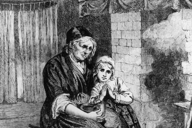 circa 1820: A mother and child living in poverty sitting close to the fire to keep warm in a bare room.