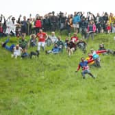 Contestants in the men’s downhill race chase the cheese down the hill in June 2022 in Gloucester, England. 