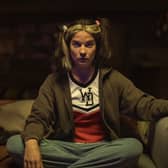 Annie Murphy as Joan in Black Mirror Season 6 episode 1 'Joan is Awful', cross legged on the sofa (Credit: Nick Wall/Netflix)