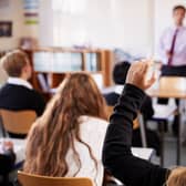 A female student raising her hand to ask a question in class. Credit: Monkey Business.