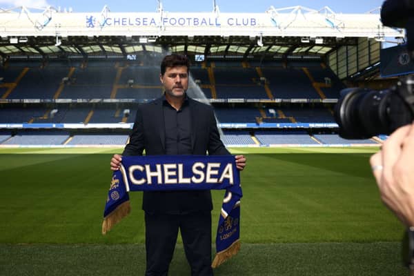 Chelsea’s Argentinian head coach Mauricio Pochettino poses for a photograph with a Chelsea scarf beside the pitch at Stamford Bridge (Photo by HENRY NICHOLLS/AFP via Getty Images)