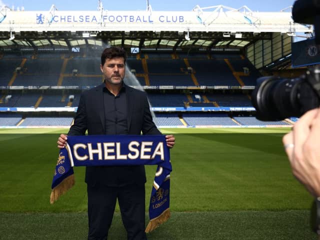 Chelsea’s Argentinian head coach Mauricio Pochettino poses for a photograph with a Chelsea scarf beside the pitch at Stamford Bridge (Photo by HENRY NICHOLLS/AFP via Getty Images)