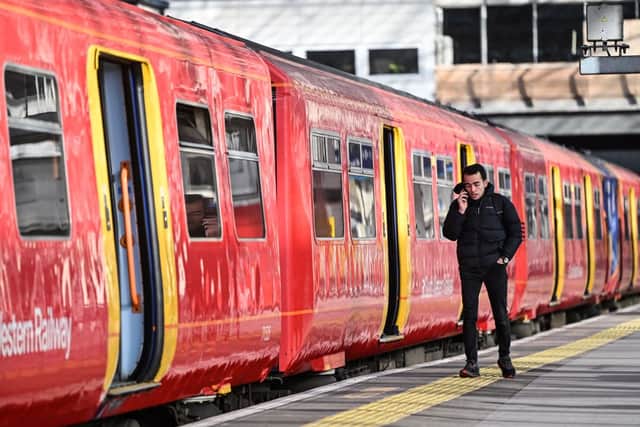A commuter walks past a train stopped at a platform in Waterloo Station in London. (Photo by JUSTIN TALLIS/AFP via Getty Images)