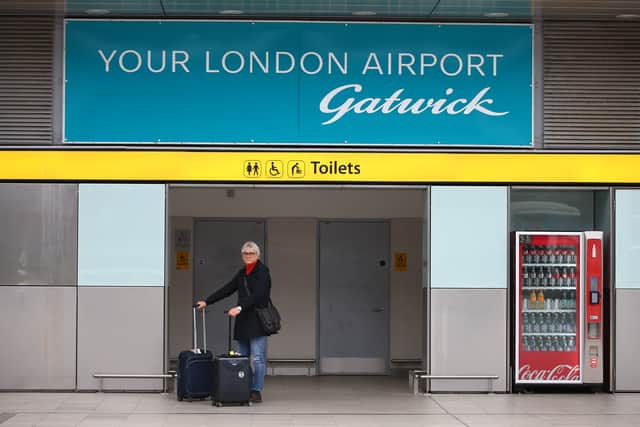 A traveller standing with luggage at Gatwick Airport. Credit: Hollie Adams/Getty Images.