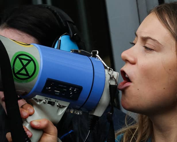 Swedish climate activist Greta Thunberg chants slogans in loud speaker as she sits in front of the entrance of the Bank JP Morgan in Canary Wharf. Credit: Daniel Leal/AFP via Getty Images.