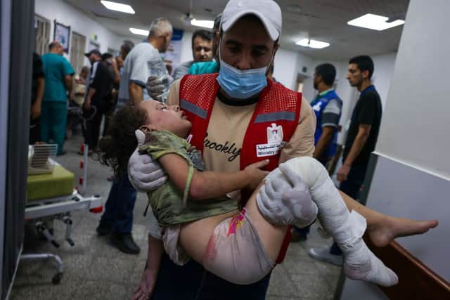 An emergency responder carries a wounded child in a hospital following Israeli airstrikes in Rafah, southern Gaza Strip,