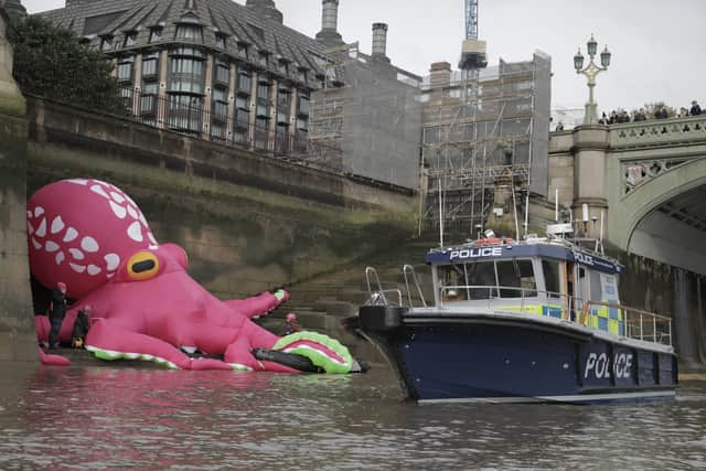 A police boat checks out the 20-metre tall octopus in the Thames (Photo: Kristian Buus / Greenpeace)