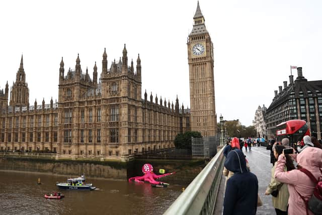 A giant inflatable Octopus is pictured on the bank of the River Thames beneath the Elizabeth Tower, commonly called Big Ben, at Britain's Houses of Parliament, during an action by Greenpeace.  (Photo by HENRY NICHOLLS/AFP via Getty Images)