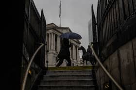 A member of the public walks through heavy rain near the Bank of England in May 2023. (Photo by Dan Kitwood/Getty Images)