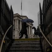 A member of the public walks through heavy rain near the Bank of England in May 2023. (Photo by Dan Kitwood/Getty Images)