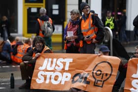 'Just Stop Oil' protesters block the road at the junction of Cannon St and Queen Victoria St on October 27, 2022 in London, England.
