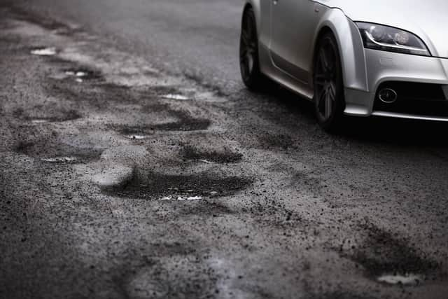 A car passing a series of potholes.  (Photo by Jeff J Mitchell/Getty Images)