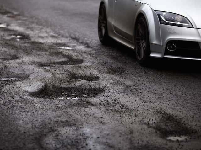A car passing a series of potholes.  (Photo by Jeff J Mitchell/Getty Images)