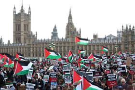 Protesters hold placards and wave Palestinian flags as they walk over Westminster Bridge 