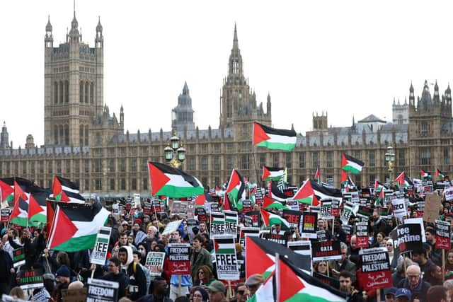 Protesters hold placards and wave Palestinian flags as they walk over Westminster Bridge 