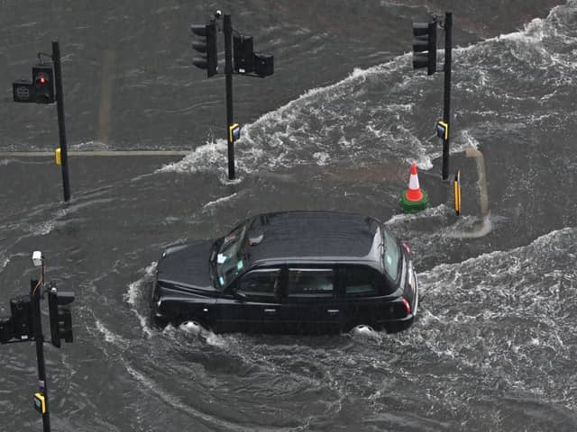  A London taxi drives through water on a flooded road in The Nine Elms district of London on July 25, 2021 during heavy rain. 