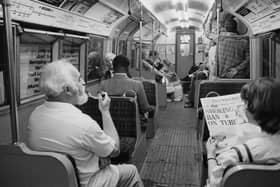 A man smoking a pipe while travelling on a London Underground Nothern Line train as a woman in the seat next to him reads a Evening Standard newspaper with title that reads 'Smoking Ban on Tube', London, UK, 21st June 1984. (Photo by D. Jones/Daily Express/Hulton Archive/Getty Images)