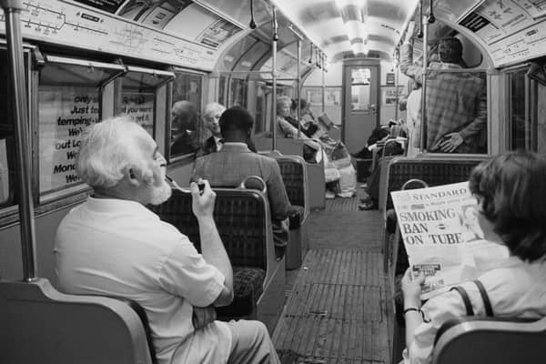 A man smoking a pipe while travelling on a London Underground Nothern Line train as a woman in the seat next to him reads a Evening Standard newspaper with title that reads 'Smoking Ban on Tube', London, UK, 21st June 1984. (Photo by D. Jones/Daily Express/Hulton Archive/Getty Images)