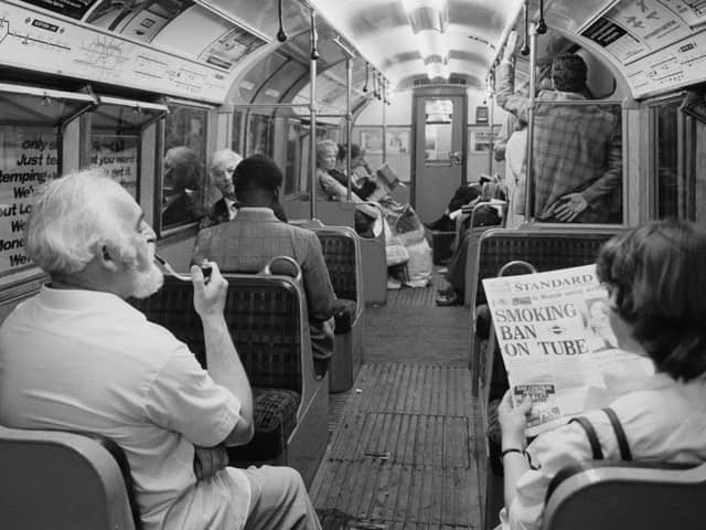A man smoking a pipe while travelling on a London Underground Nothern Line train as a woman in the seat next to him reads a Evening Standard newspaper with title that reads 'Smoking Ban on Tube', London, UK, 21st June 1984. (Photo by D. Jones/Daily Express/Hulton Archive/Getty Images)