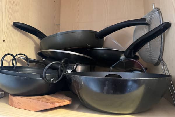 A kitchen cupboard full of pans.