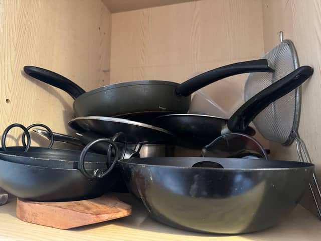 A kitchen cupboard full of pans.