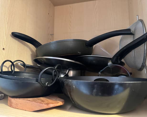 A kitchen cupboard full of pans.