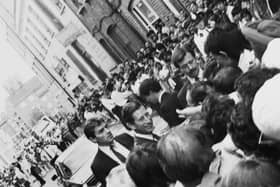 Prince Charles meeting the public in Brick Lane in 1987 while bodyguards look on and police hold back crowds.