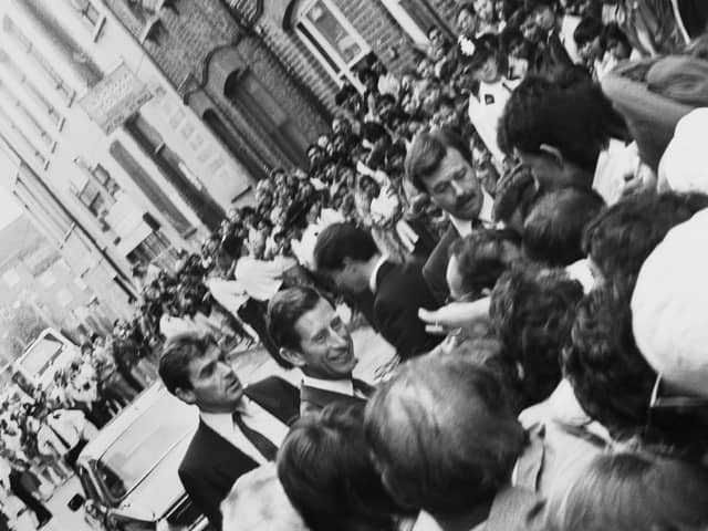 Prince Charles meeting the public in Brick Lane in 1987 while bodyguards look on and police hold back crowds.