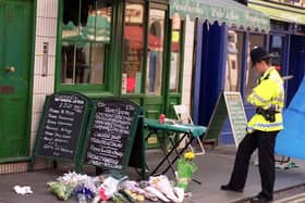 An policeman views floral tributes on the pavement near the scene of a bomb blast in Soho on May 1 1999. Two people died and more than 70 were injured after a nail bomb exploded.