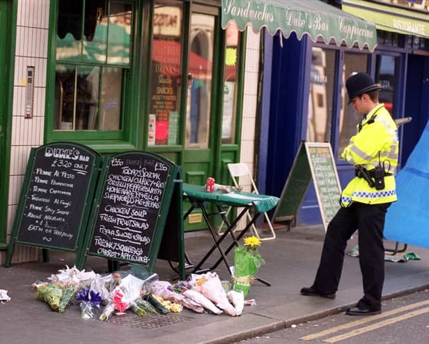 An policeman views floral tributes on the pavement near the scene of a bomb blast in Soho on May 1 1999. Two people died and more than 70 were injured after a nail bomb exploded.