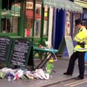 An policeman views floral tributes on the pavement near the scene of a bomb blast in Soho on May 1 1999. Two people died and more than 70 were injured after a nail bomb exploded.