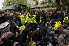 Police officers prepare to move protesters surrounding a bus that was to be used to carry migrants from a hotel in Peckham