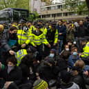 Police officers prepare to move protesters surrounding a bus that was to be used to carry migrants from a hotel in Peckham