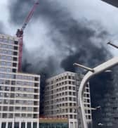 Thick black smoke can be seen billowing between buildings
