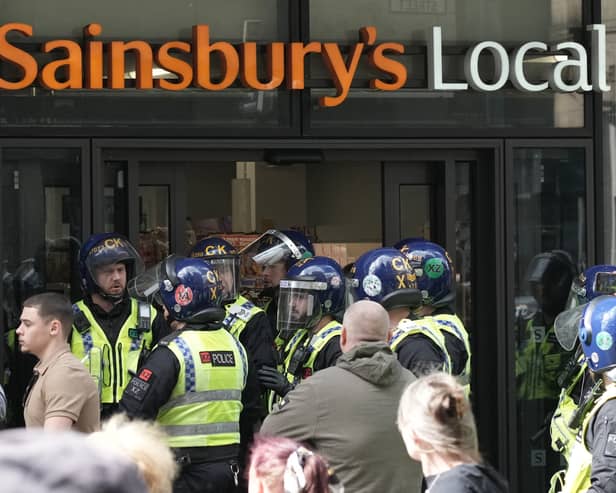 Police gather outside the Sainsbury’s local that was targeted by looters. 