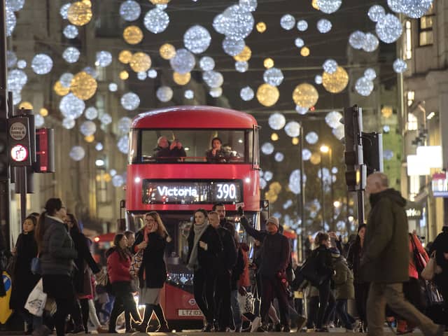 Shoppers cross in front of a London bus as it travels under Christmas lights on Oxford Street in central London in 2017 (Photo: JUSTIN TALLIS/AFP via Getty Images)