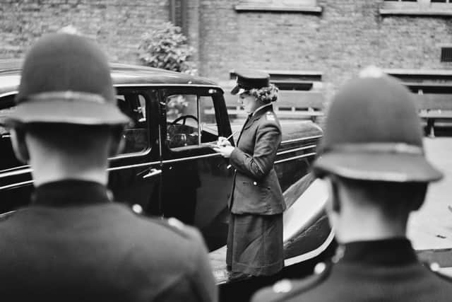 A female Metropolitan Police cadet writing out a ticket for  a careless driver in a role play during a Traffic Control class at Peel House
