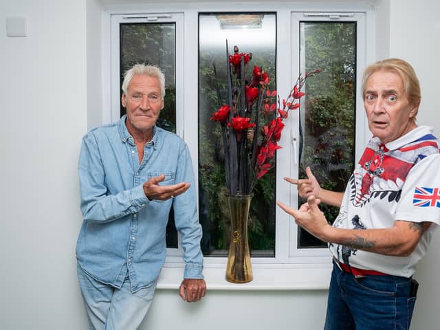 Residents Ian Hunter (L) and Thomas Dunn (R) standing in their hallway next to a vase of flowers.