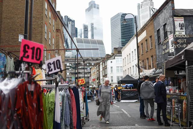 Shoppers browse stalls in Petticoat Lane Market, against the backdrop of The City of London financial district